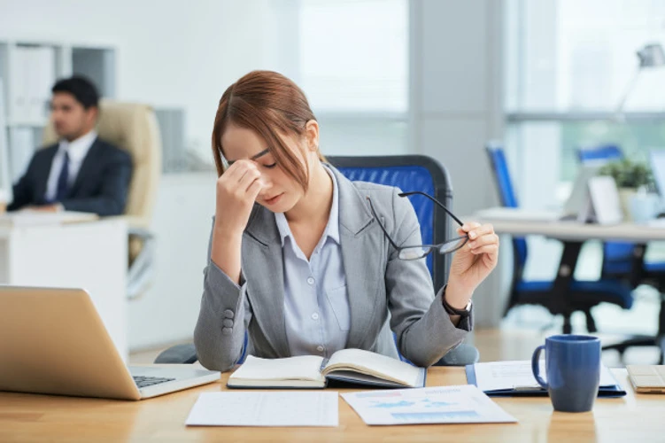 A office lady feeling exhausted in front of the laptop and a bunch of task