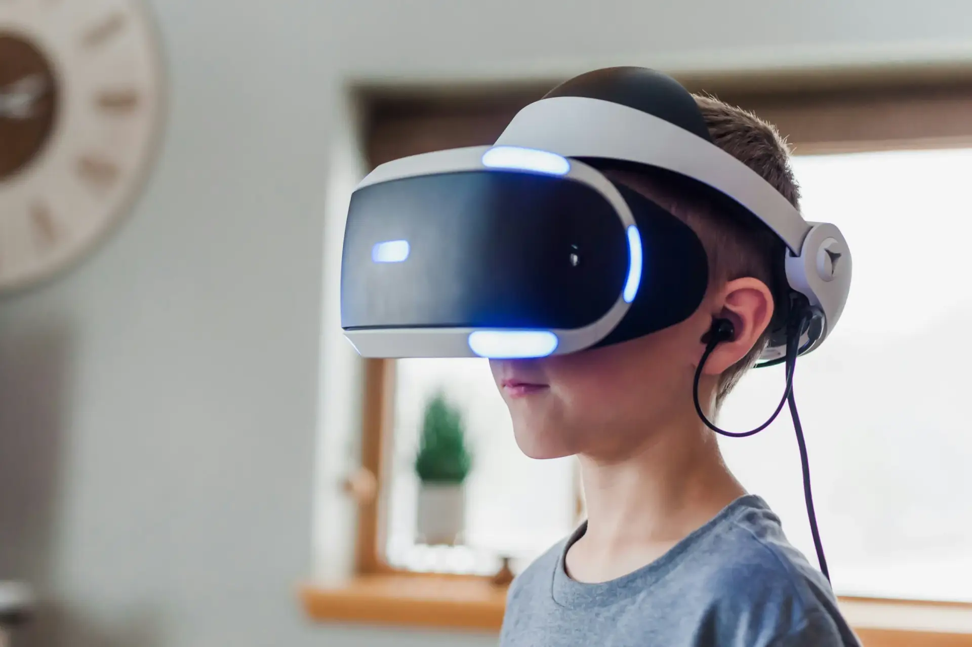 A young boy engages with virtual reality, donning a headset while seated in a comfortable living room.